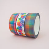 Three washi tape rolls in a row. A colourful pastel rainbow check, a dusky rainbow check, and a bright colour wheel pattern with silver-foil dots.
