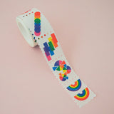 Roll of washi tape in a stamp style with perforated edges. Each stamp has a different design featuring rainbows and brightly coloured shapes.