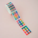 Roll of washi tape in a stamp style with perforated edges. Each stamp has a different, colourful gingham-patterned design.