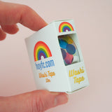 A colourful roll of washi tape in a gold foil-printed, windowed box.