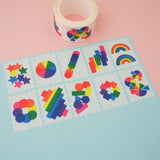 Ten stamps cut from a roll of washi tape with perforated edges. Each stamp has a different design featuring rainbows and brightly coloured shapes. They are arranged in two rows of five on a pale blue card.