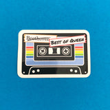 Sticker depicting a black cassette tape. The centre of the tape is blue with a rainbow stripe. At the top the word Beethoven has been scored out and the words Best of Queen are written in capital letters. Sticker has a white border.