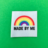 Pale blue clothing label with the words made by me in black capital letters and a bright rainbow above. The label is on a bright green background.