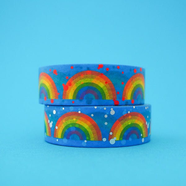Stack of two rolls of blue washi tape featuring rainbows and silver or red foil accents.