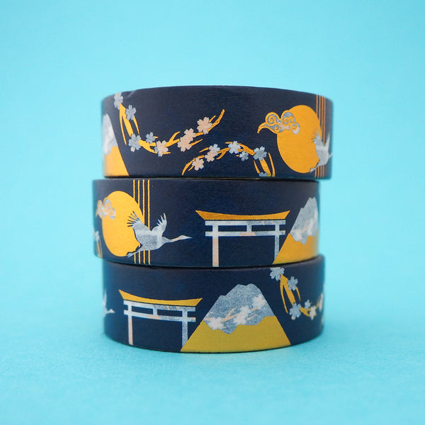 Stack of deep blue washi tape featuring cranes, cherry blossom, Mount Fuji and torii gates in white with gold-foil accents.