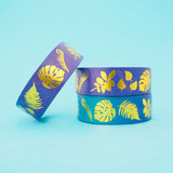 Stack of purple and blue gradient washi tape with a variety of gold-foil plants and leaves.
