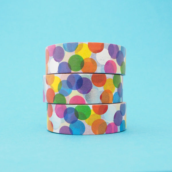 Stack of white washi tape with a scattered design of colourful circles. The colours change where the circles overlap. Accented with silver foil circles.