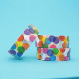 Stack of white washi tape with a scattered design of colourful circles. The colours change where the circles overlap. Accented with silver foil circles.