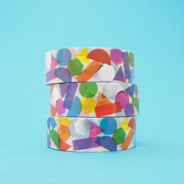 Stack of white washi tape with a scattered design of colourful shapes. The colours change where the shapes overlap. Accented with silver foil shapes.