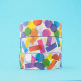 Stack of three white washi tape with a scattered design of colourful shapes. One has circles, one has rectangles. and the third has a variety of shapes. The colours change where the shapes overlap. Accented with silver foil.