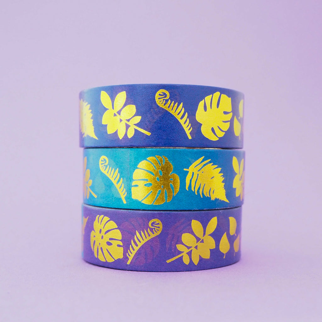 Stack of purple and blue gradient washi tape with a variety of gold-foil plants and leaves.