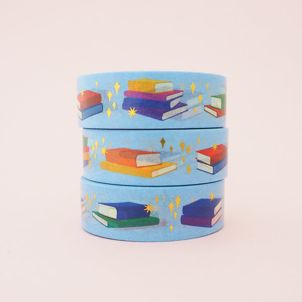 Light blue washi tape printed with small stacks of colourful books and gold-foil sparkles.