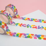 Three rolls of white washi tape with a scattered design of colourful shapes. One has circles, one has rectangles. and the third has a variety of shapes. The colours change where the shapes overlap. Accented with silver foil.