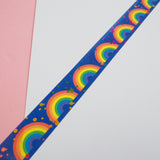 Strip of deep blue washi tape featuring rainbows and colourful foil accents.