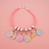 Pink cord bracelet threaded with multiple enamel charms on smooth cup bail beads. Charms are of various pastel-coloured designs.