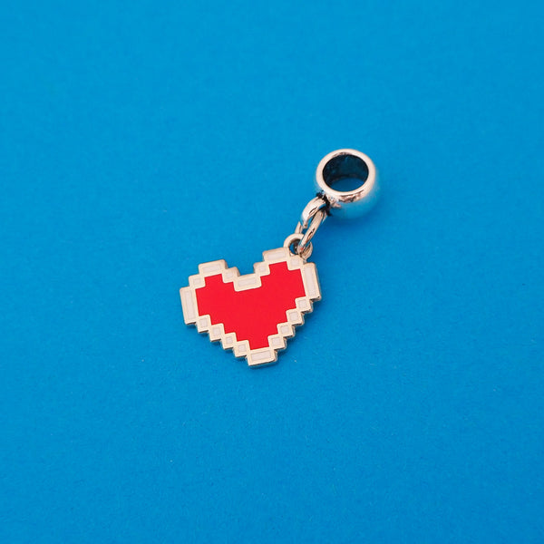 Enamel charm on a smooth cup bail bead. Charm depicts a red, pixelated heart with a white outline.