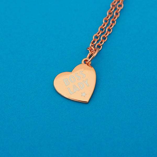 Rose-gold plated necklace with a rose-gold plated charm pendant. Charm is heart-shaped and Boss Lady in white capitals with a little white star beneath.