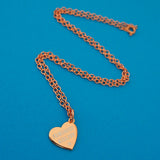 Rose-gold plated curb chain necklace with a rose-gold charm pendant. Charm is heart-shaped and bears the words Feminist Killjoy in white capital letters with a small white star beneath.