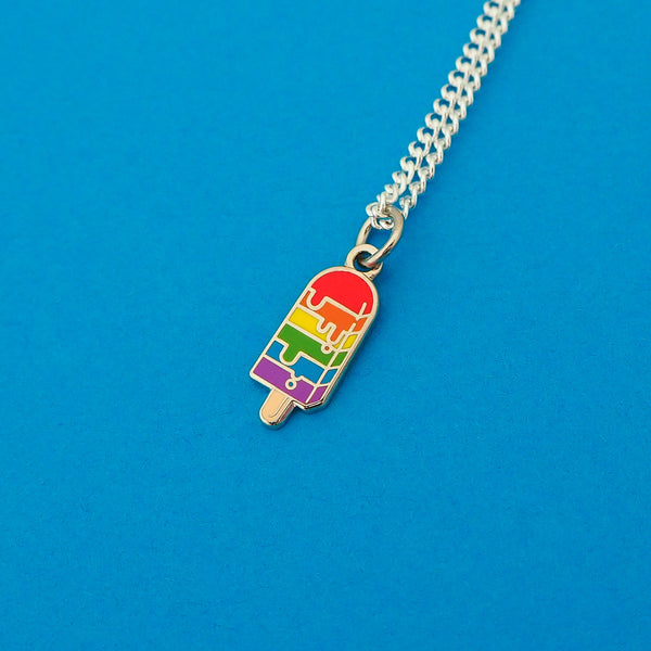 Silver plated curb chain necklace with an enamel charm pendant. Charm is in the shape of an ice lolly and has horizontal rainbow stripes with the bright colours dripping into neighbouring sections like it is melting.