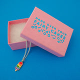 Silver plated curb chain necklace with an enamel charm pendant. Charm is in the shape of an ice lolly and has horizontal rainbow stripes with the bright colours dripping into neighbouring sections like it is melting. Necklace is shown emerging from a pink branded box.