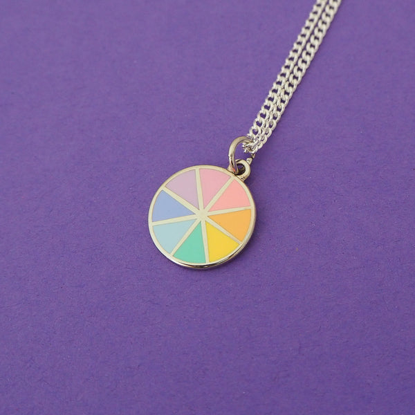 Silver-plated curb chain necklace with an enamel charm pendant. Charm is circular and split into eight sections. Each section is filled with a pastel rainbow colour, replicating a colour wheel.