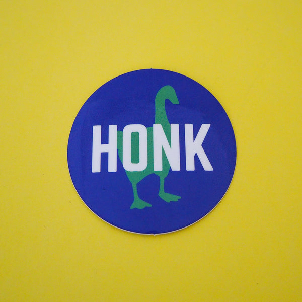 Round vinyl sticker that is deep blue with the word Honk written in the centre in white capital letters. Behind the word is a green silhouette of a goose.