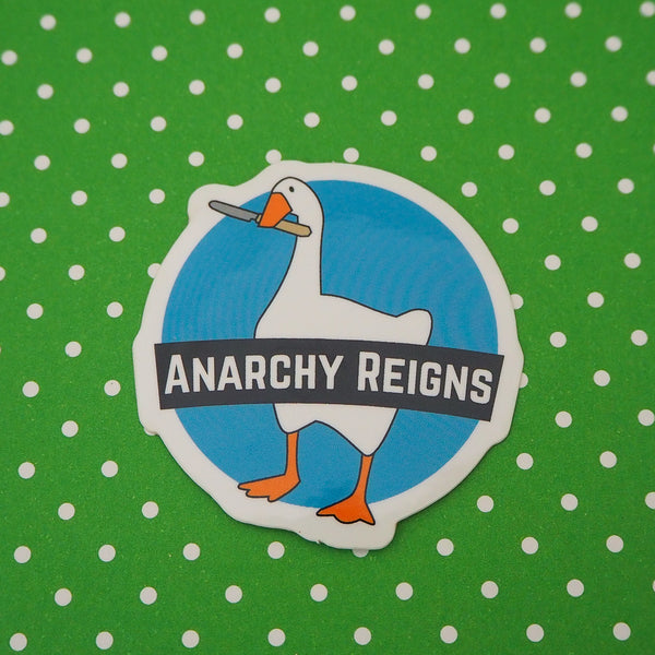 A circular, light blue sticker depicting a goose with a knife in its beak. A banner across the middle reads Anarchy Reigns. The sticker has a white border.