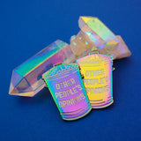 Two rainbow-plated metal pins in the shape of a rubbish bin which reads Other People's Opinions in white capitals. The pins are resting on quartz crystals.