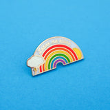 Metal pin showing a rainbow with sun and lightning cloud that reads Leave Me Alone in silver script.