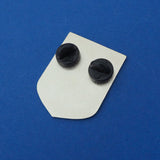 The back of a shield-shaped enamel pin with two black rubber backings. Pin is on a deep blue background.