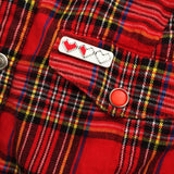 Rectangular enamel pin on a red tartan shirt. The pin is showing three pixelated hearts. The first heart is filled red, the second is filled red on the left half and white on the right, the third heart is filled white.