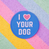 Round embroidered patch that reads I heart Your Dog in white capitals. The background is blue and the heart is pastel pink. The patch has blue merrowed edges.