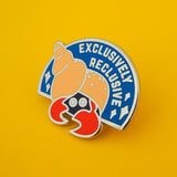 Semi-circular, blue enamel pin with the image of a hermit crab in a peach coloured spiral shell. Only the crabs eyes and red claws are visible, peeking out from the darkness of the shell's entrance. The words Exclusively Reclusive are written on the blue section in silver capital letters with some silver sparkles. The pin is on a yellow background.