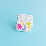 Enamel pin in the shape of a paper bag full of brightly coloured sweets.  Pin is on a light blue background.