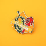 Enamel pin featuring a green leaf and red maraca on a korok seed background, a banner at the bottom reads Seed Collector. The pin is on a yellow background.