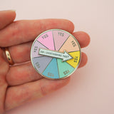 Am I Overthinking This? - Enamel Pin - Hand Over Your Fairy Cakes - hoyfc.comACircular enamel pin divided into eight pastel coloured sections. Each section has the word Yes in capital letters. There is a white arrow that can spin to point to any section with the words Am I Overthinking This? The pin is shown on a hand for scale, it is about two and a half fingers in circumference.